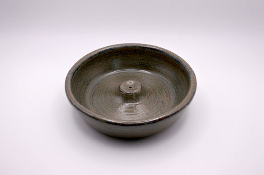 circular incense burner with textured surface in tones of forest green, olive, brown, and dark grey