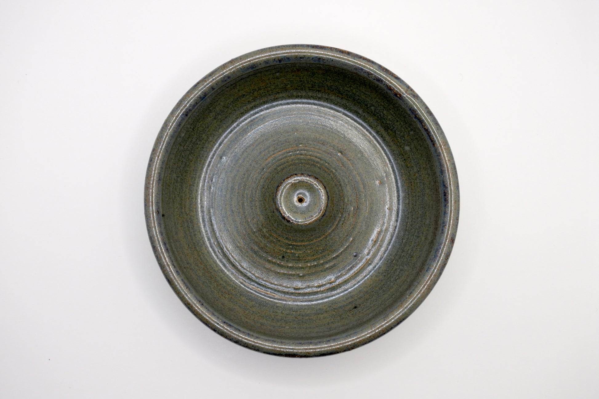 circular incense burner with textured surface in tones of forest green, olive, brown, and dark grey